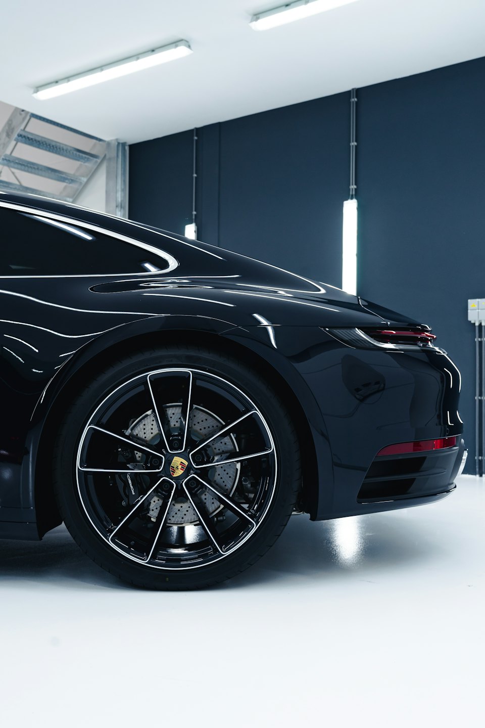 Elegantný čierny športový automobil zaparkovaný v interiéri s lesklou karosériou.