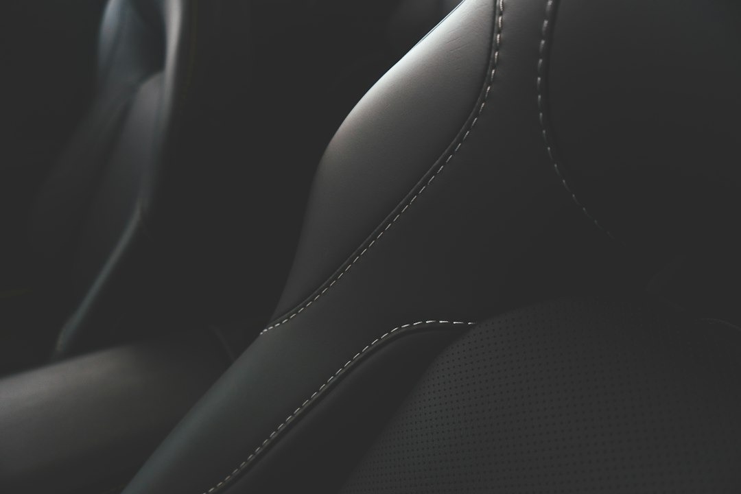 Black leather car seat with white stitching detail.